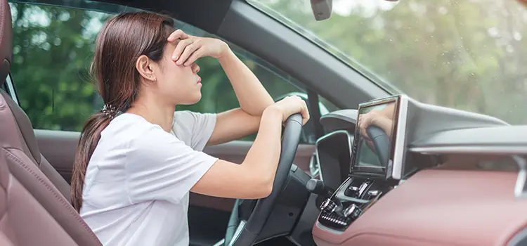 A photo of a young female driver holding their forehead.