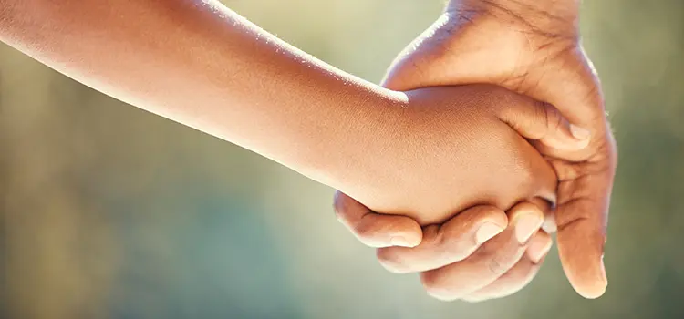 A photo of an adult holding a child's hand.