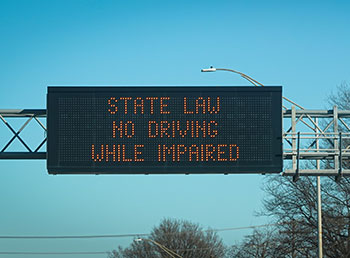 A traffic sign that reads 'State Law No Driving While Impaired'.