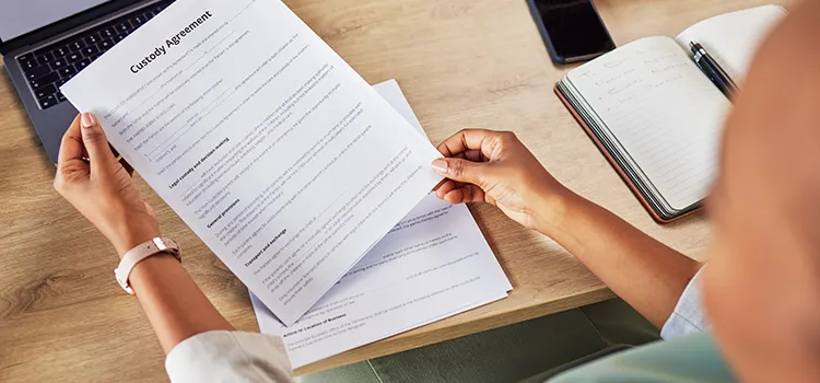 A photo of someone sitting at a desk and reviewing a custody agreement.