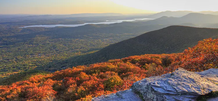 A photo looking out over the Hudson Valley during autmn from atop a cliff.