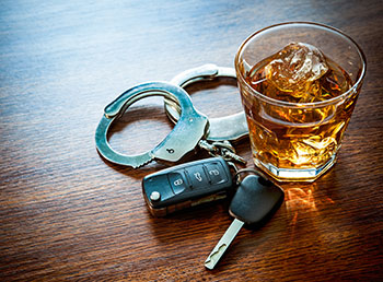 A photo of a filled whiskey glass sitting on a table next to car keys.